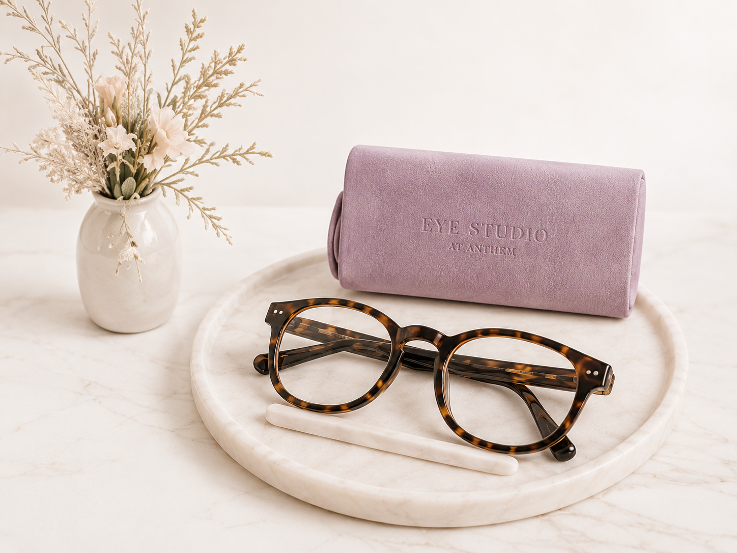Eyeglasses and mauve case arranged on a marble tray